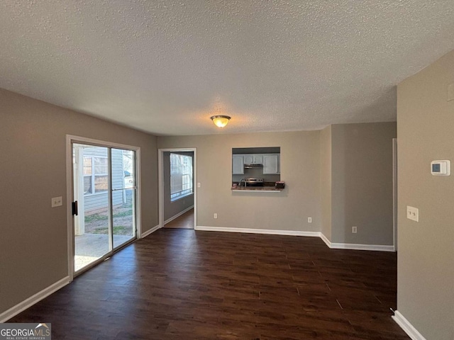 unfurnished living room featuring dark wood-type flooring and a textured ceiling