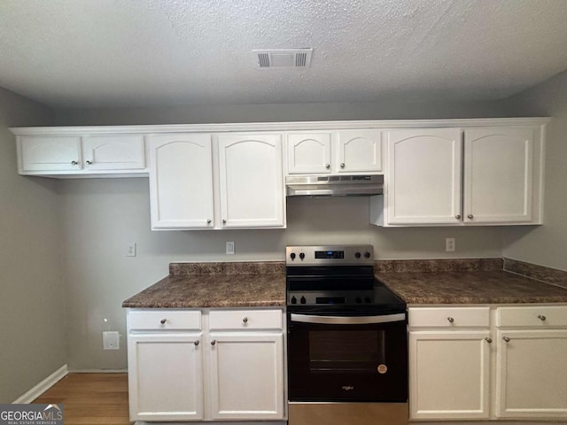 kitchen with light hardwood / wood-style floors, white cabinets, a textured ceiling, and electric stove