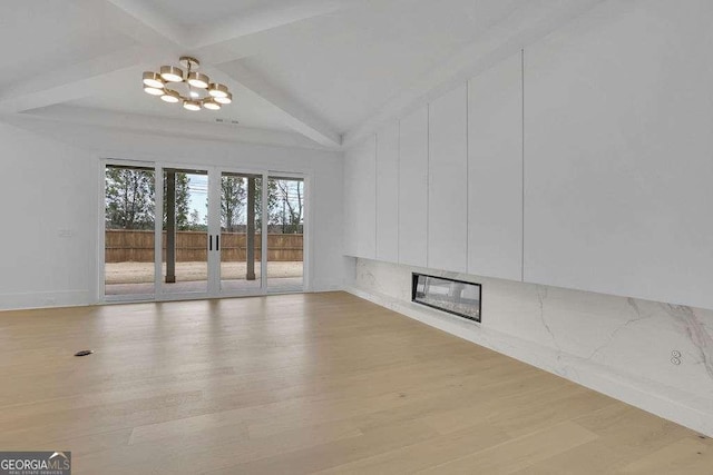 interior space with a notable chandelier, beam ceiling, and light wood-type flooring