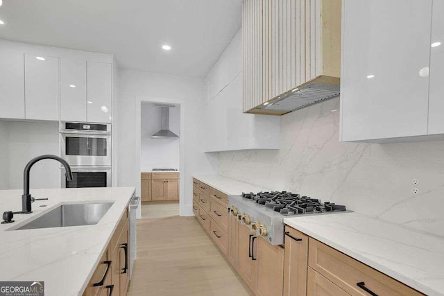 kitchen with appliances with stainless steel finishes, sink, white cabinets, and light stone counters