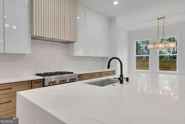 kitchen featuring white cabinetry, stove, sink, and pendant lighting