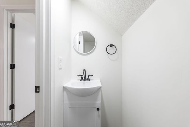 bathroom with vanity, vaulted ceiling, wood-type flooring, and a textured ceiling