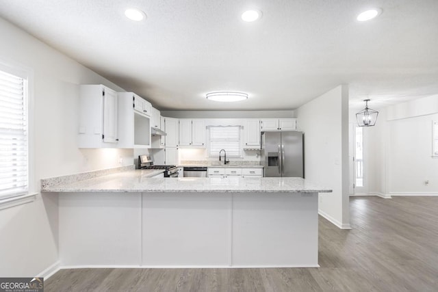 kitchen featuring hanging light fixtures, white cabinetry, appliances with stainless steel finishes, and kitchen peninsula