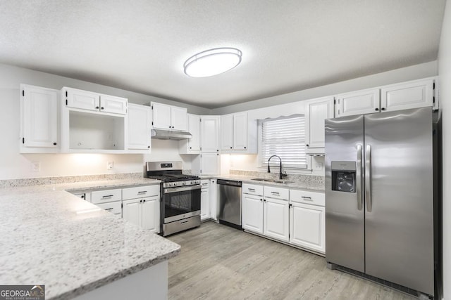 kitchen featuring sink, a textured ceiling, light wood-type flooring, appliances with stainless steel finishes, and white cabinets