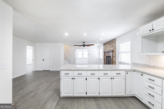 kitchen with light hardwood / wood-style flooring, white cabinets, a fireplace, and kitchen peninsula