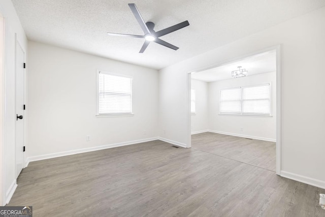 unfurnished room with ceiling fan, wood-type flooring, a textured ceiling, and a wealth of natural light