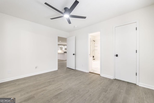 unfurnished bedroom featuring ceiling fan, ensuite bath, and light hardwood / wood-style flooring