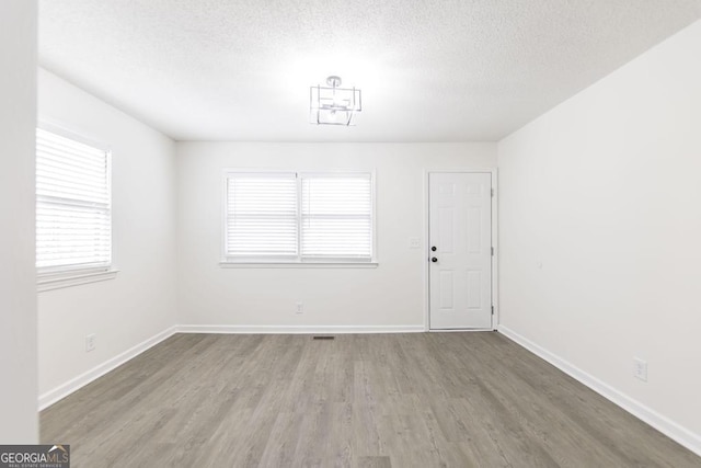 unfurnished room featuring hardwood / wood-style flooring and a textured ceiling