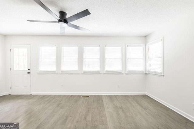 empty room with wood-type flooring, a textured ceiling, and ceiling fan