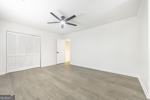 unfurnished bedroom with crown molding, hardwood / wood-style floors, ceiling fan, and a closet