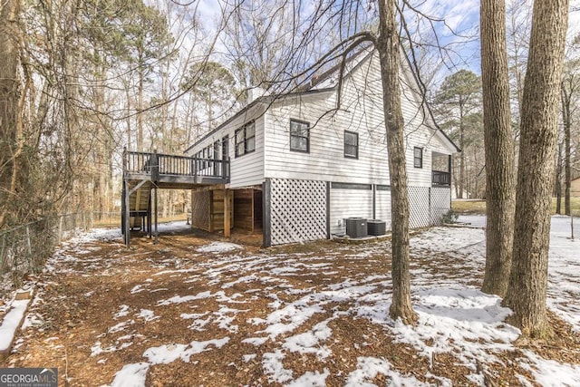 view of snowy exterior featuring a wooden deck and central AC unit