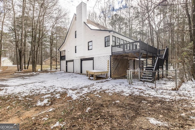 view of snowy exterior featuring a wooden deck and a garage