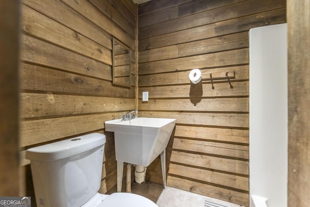 bathroom with wooden walls and toilet