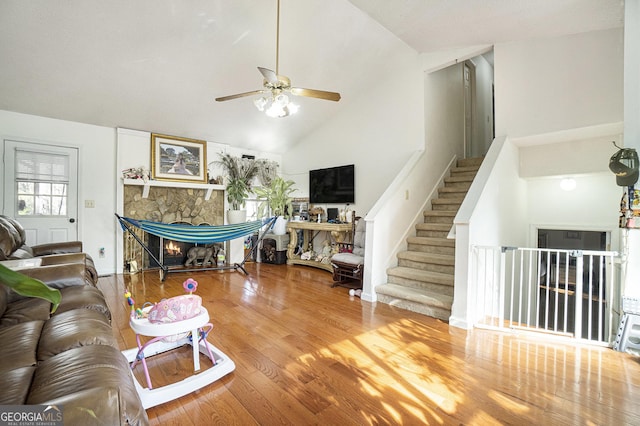 living room with hardwood / wood-style floors, a fireplace, high vaulted ceiling, and ceiling fan