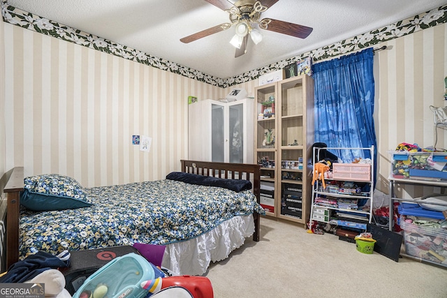 bedroom with ceiling fan, carpet, and a textured ceiling