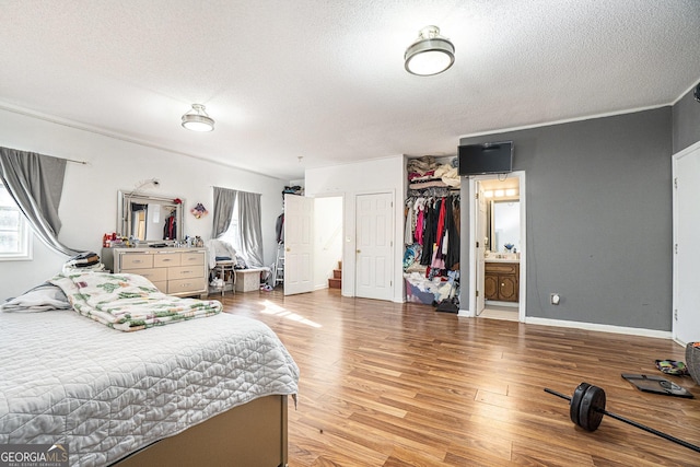 bedroom with sink, ensuite bath, a textured ceiling, a closet, and light hardwood / wood-style floors