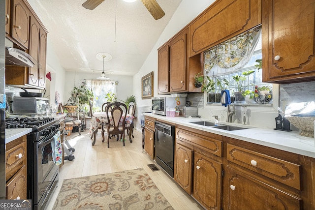 kitchen featuring sink, gas range, hanging light fixtures, light wood-type flooring, and dishwasher