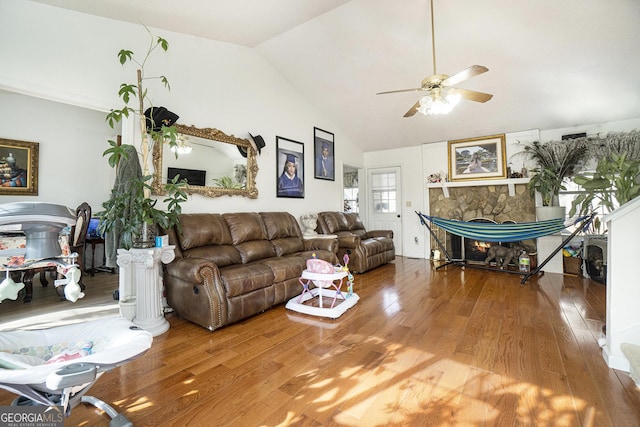 living room with vaulted ceiling, ceiling fan, a fireplace, and hardwood / wood-style floors