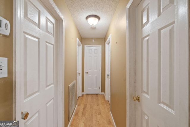 hall with light hardwood / wood-style flooring and a textured ceiling