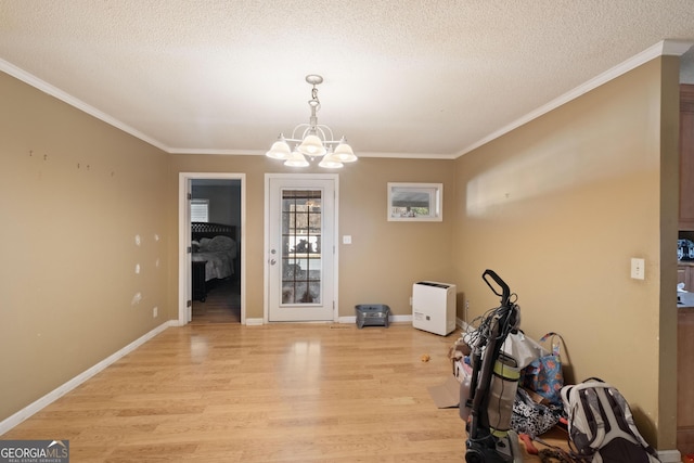 interior space with crown molding, a chandelier, a textured ceiling, and light hardwood / wood-style floors