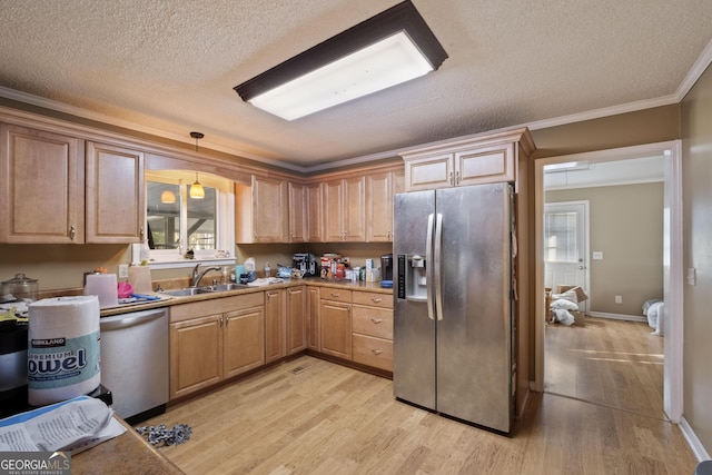 kitchen featuring sink, light wood-type flooring, ornamental molding, appliances with stainless steel finishes, and pendant lighting