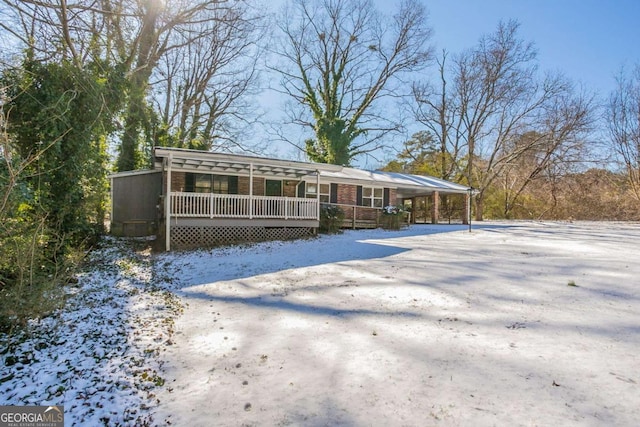 snow covered back of property featuring covered porch