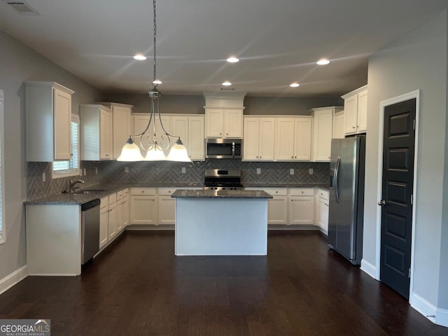 kitchen with white cabinetry, appliances with stainless steel finishes, dark hardwood / wood-style flooring, a kitchen island, and pendant lighting