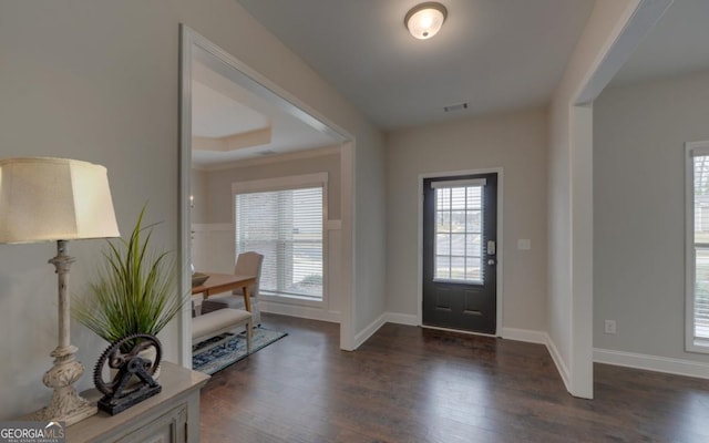 foyer with crown molding, a tray ceiling, and dark hardwood / wood-style floors