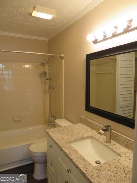 full bathroom featuring crown molding, vanity, toilet, and a textured ceiling