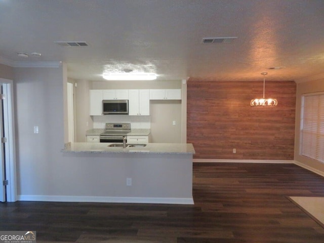 kitchen featuring wood walls, white cabinetry, light stone counters, hanging light fixtures, and stainless steel appliances