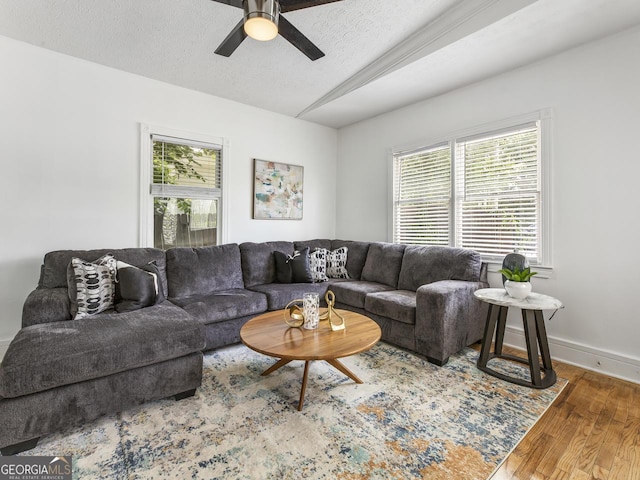 living room featuring ceiling fan, lofted ceiling, hardwood / wood-style floors, and a textured ceiling