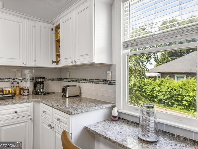 kitchen with light stone counters, backsplash, and white cabinets