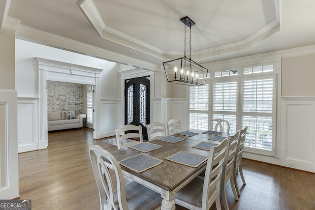 dining area featuring a healthy amount of sunlight, a tray ceiling, and hardwood / wood-style floors