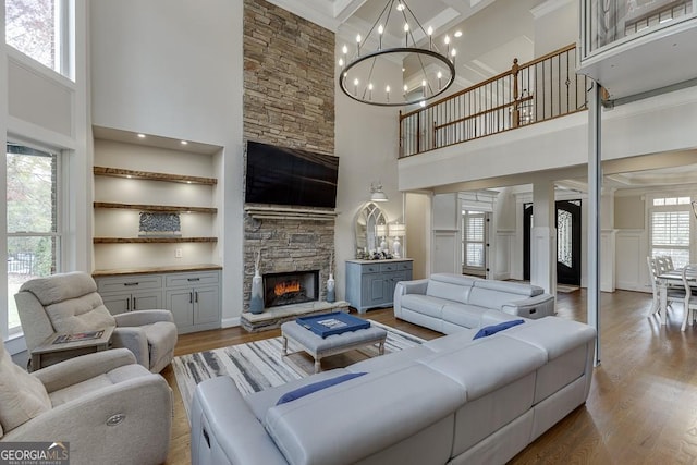 living room with hardwood / wood-style flooring, a towering ceiling, a fireplace, and a chandelier