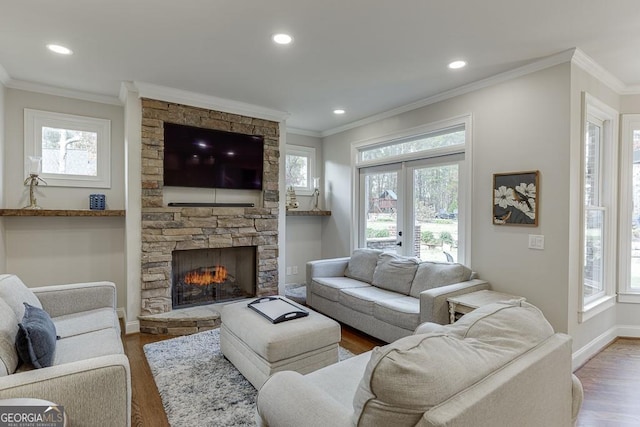 living room with a stone fireplace, dark wood-type flooring, ornamental molding, and french doors