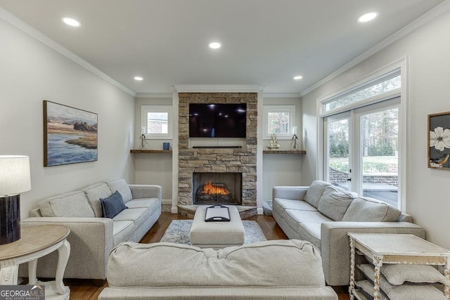 living room featuring crown molding, hardwood / wood-style flooring, and a stone fireplace