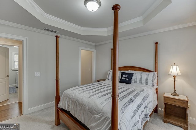 bedroom with crown molding, light colored carpet, and a tray ceiling