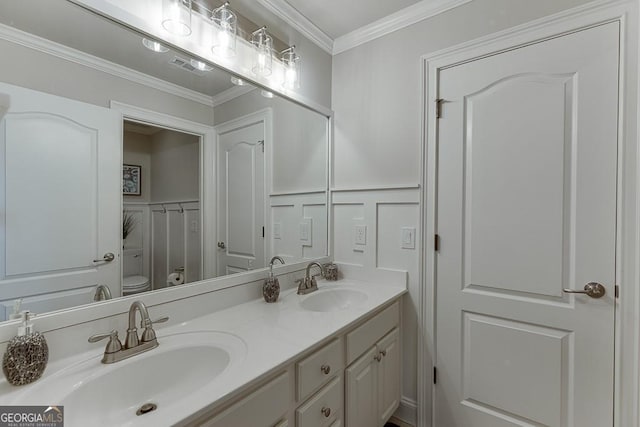 bathroom with ornamental molding, vanity, and toilet