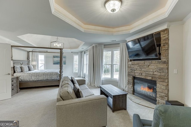 carpeted bedroom featuring crown molding, a notable chandelier, a tray ceiling, and a fireplace