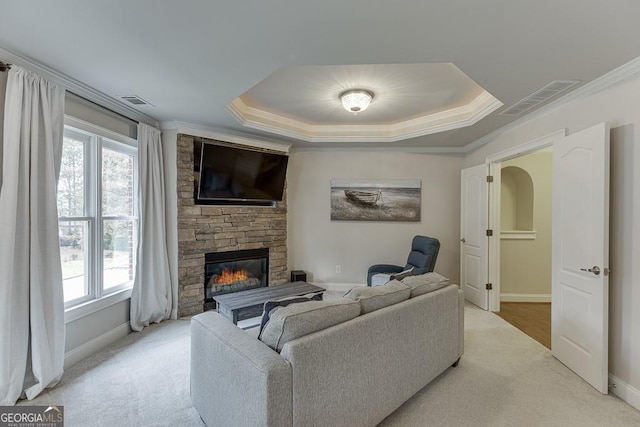 carpeted living room with a raised ceiling, crown molding, and a fireplace