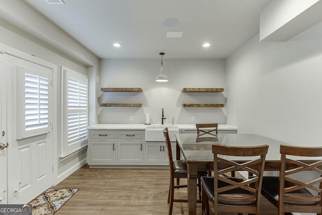 interior space with sink, pendant lighting, and light hardwood / wood-style flooring