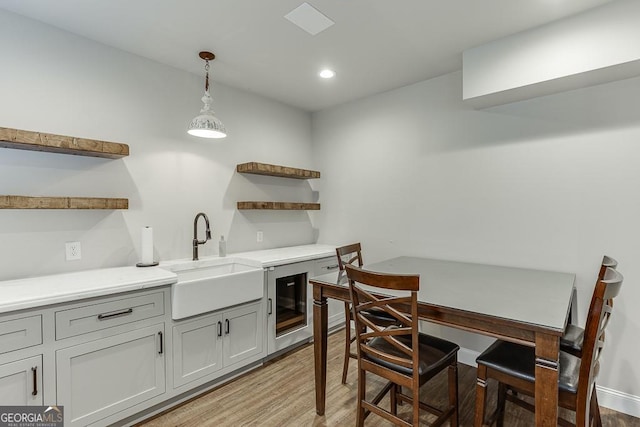 kitchen with sink, hanging light fixtures, and light wood-type flooring