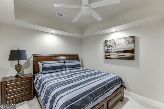 carpeted bedroom featuring ceiling fan and a tray ceiling