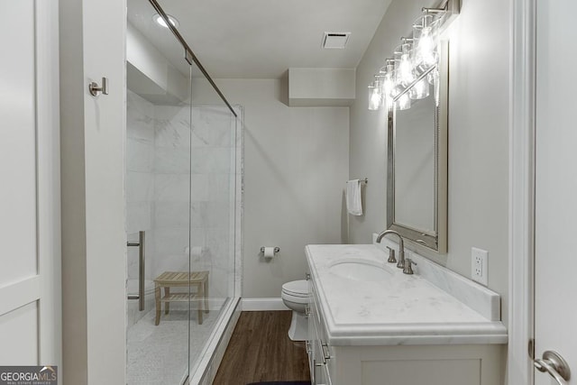 bathroom featuring vanity, hardwood / wood-style flooring, a shower with shower door, and toilet