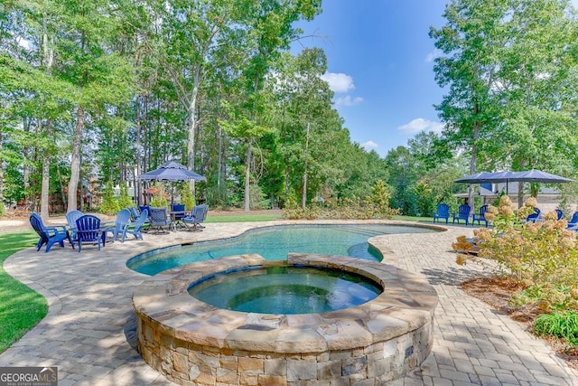 view of pool with an in ground hot tub and a patio