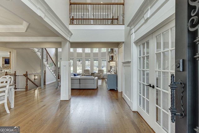 foyer featuring hardwood / wood-style floors, crown molding, french doors, and a high ceiling