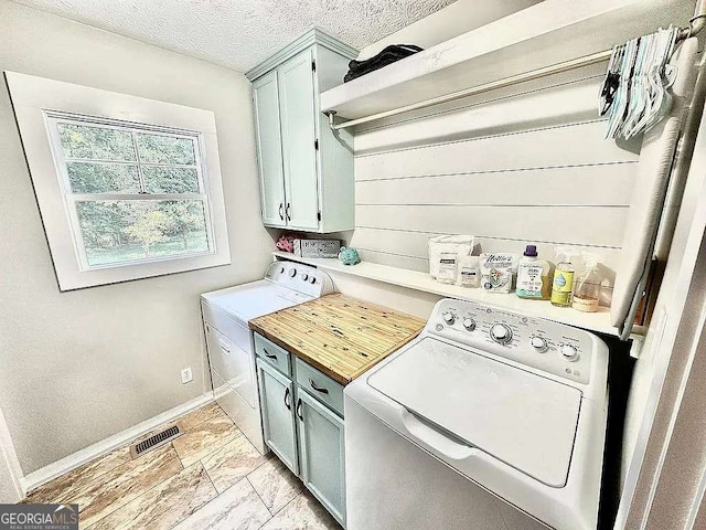 laundry area featuring cabinets, a textured ceiling, and independent washer and dryer