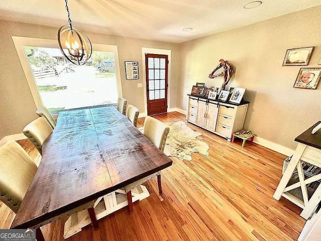 dining space with hardwood / wood-style floors and a notable chandelier