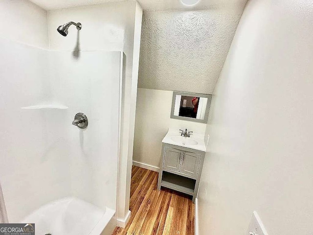 bathroom with vanity, hardwood / wood-style flooring, a textured ceiling, and a shower