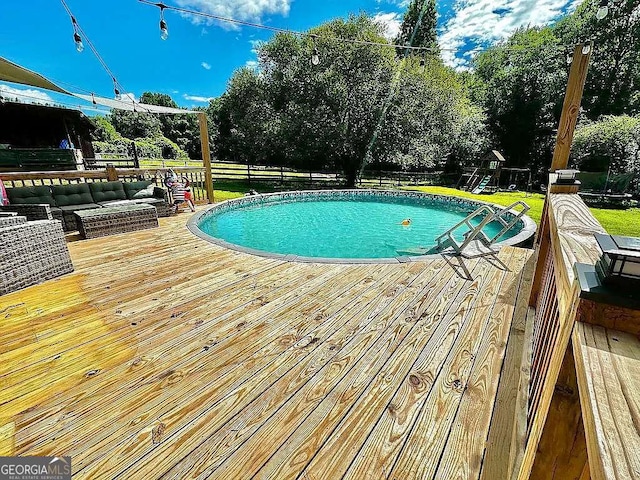 view of swimming pool featuring an outdoor living space, a deck, and a playground